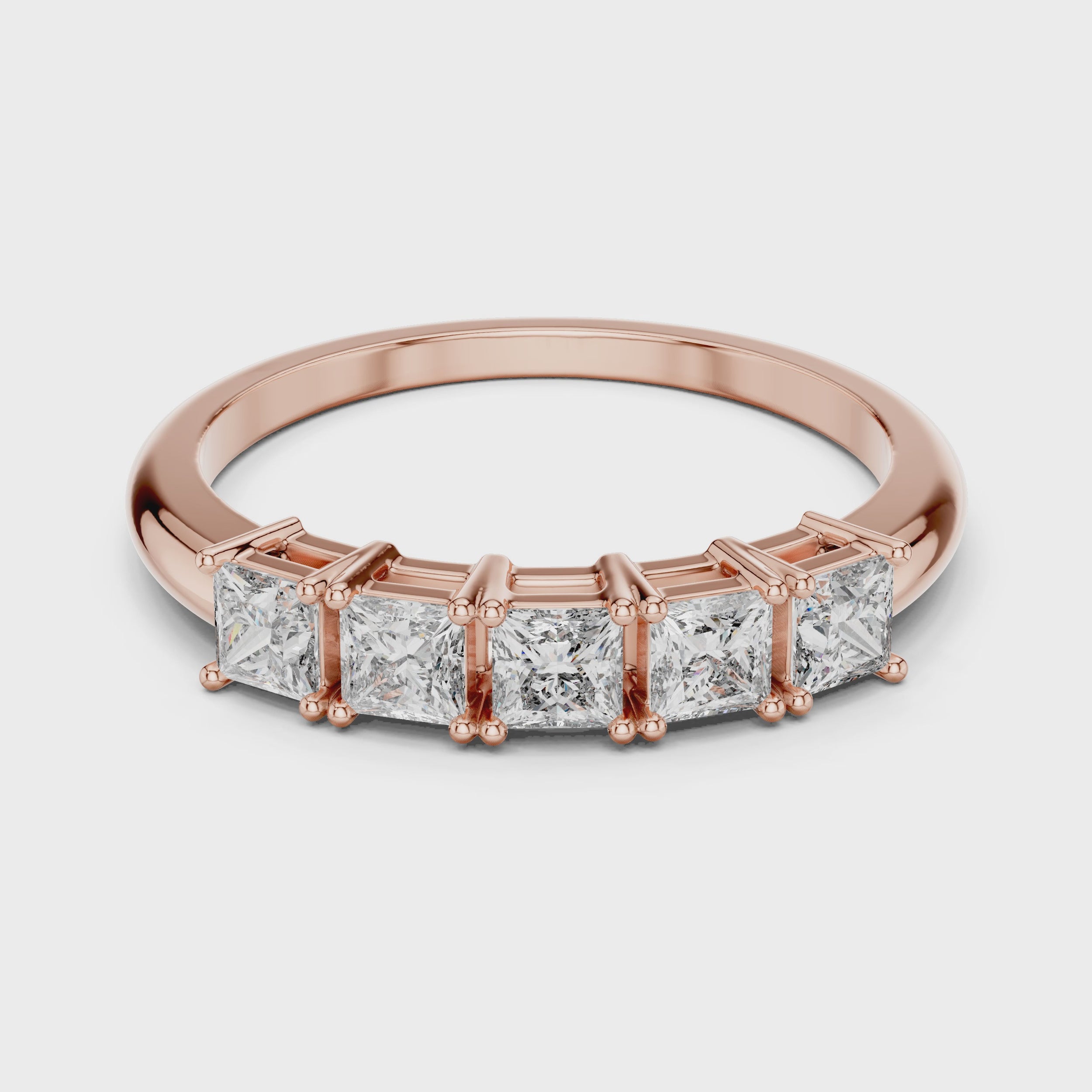 Rose gold ring with clear diamonds is rotating horizontally on a white surface.