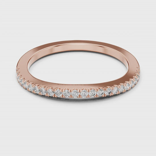 Rose gold ring with natural round diamonds on a white surface is rotating.