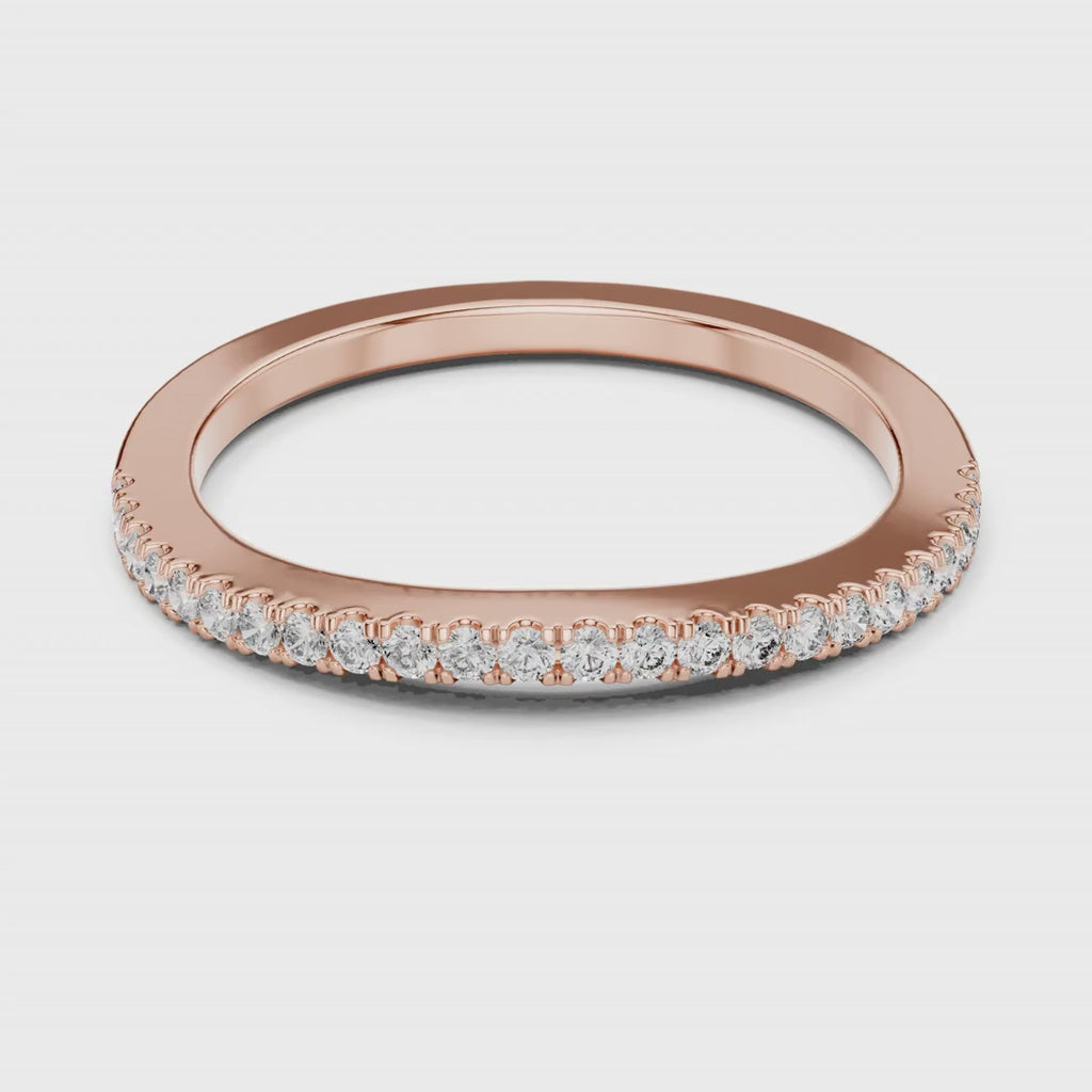 Rose gold ring with natural round diamonds on a white surface is rotating.