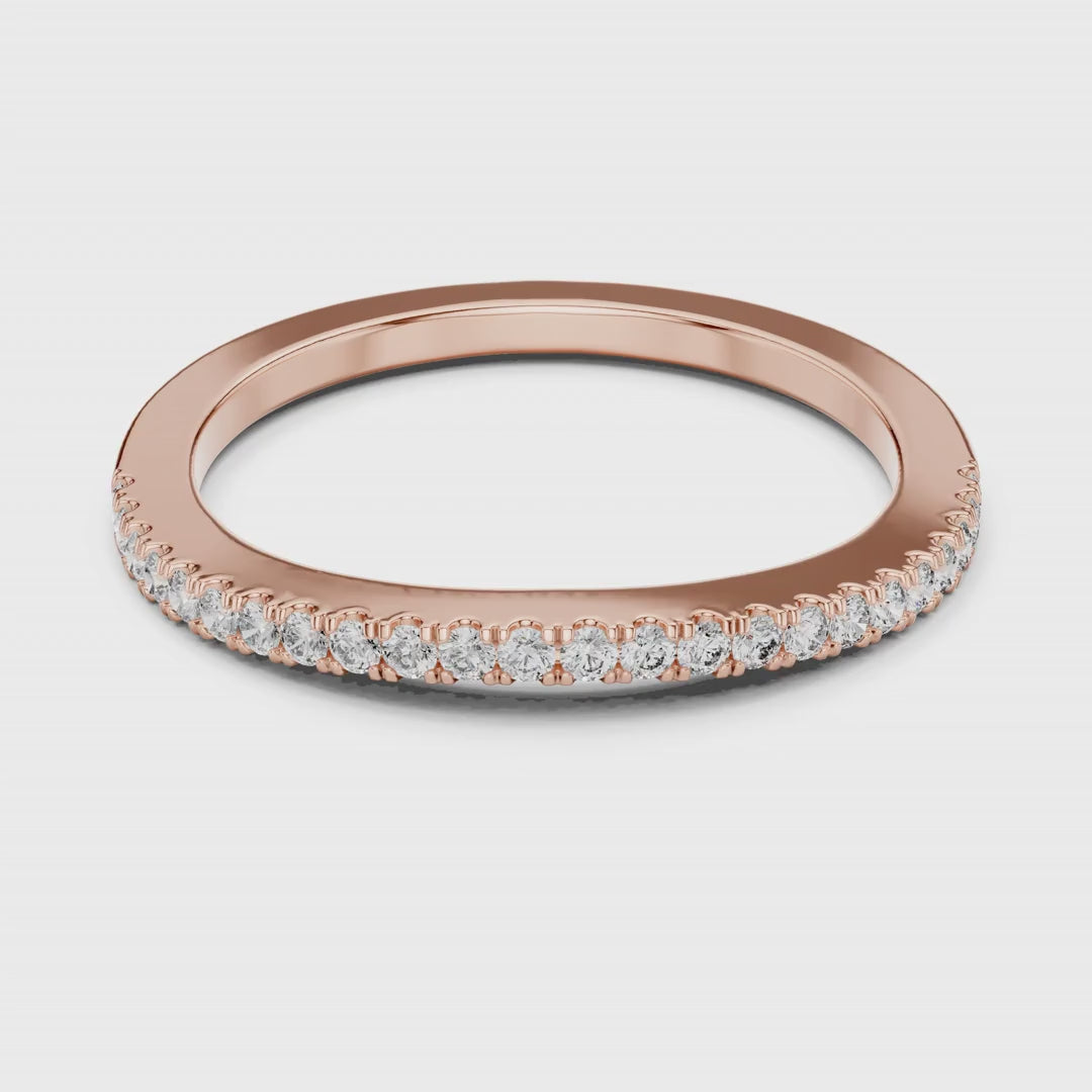 Rose gold ring with natural round diamonds on a white surface is rotating.