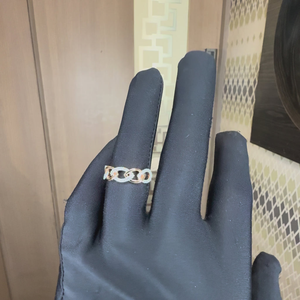 A close-up of a hand with black gloves wearing a delicate rose gold ring with small clear stones, set against a neutral background, showing the ring from every angle.