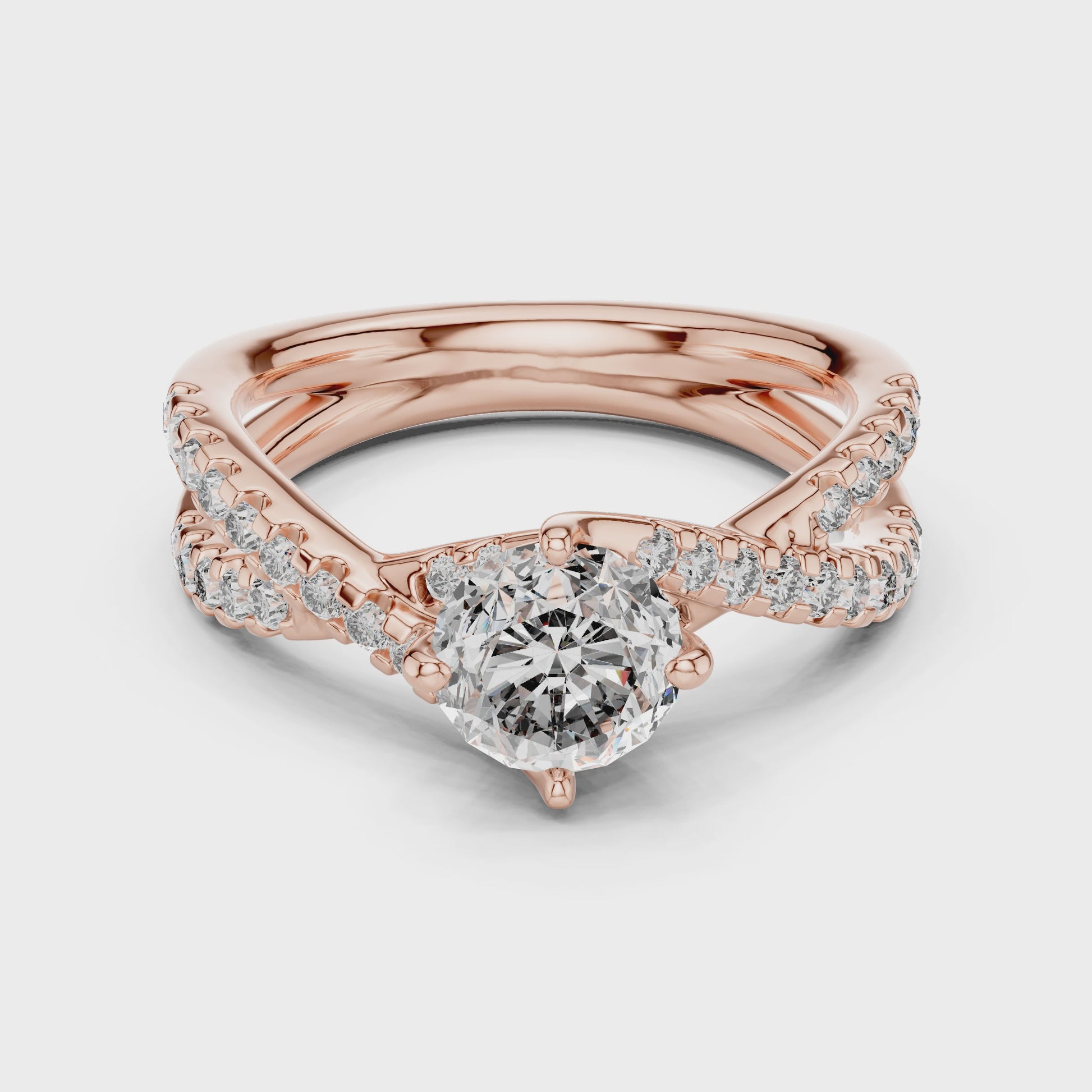 A rose gold ring with diamonds is rotating horizontally on a white surface. The ring has 1 large diamond in the center and other small diamonds are studded on a shank.