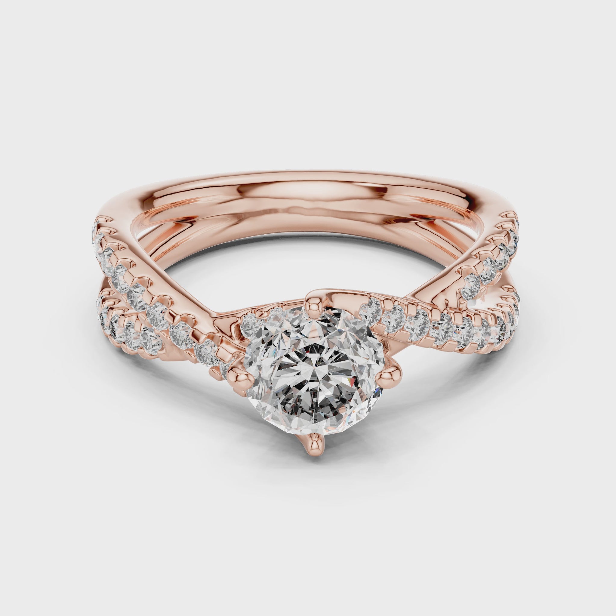 A rose gold ring with diamonds is rotating horizontally on a white surface. The ring has 1 large diamond in the center and other small diamonds are studded on a shank.