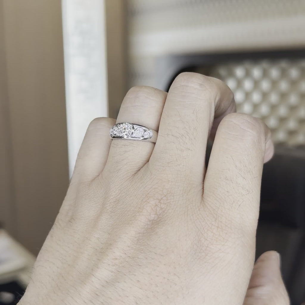 A person's hand that is worn white gold ring diamond studded, is showing the ring from the closeup tilting hand a little against a office background.