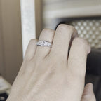 A person's hand that is worn white gold ring diamond studded, is showing the ring from the closeup tilting hand a little against a office background.