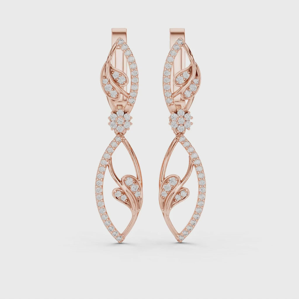 Rose gold earrings with pave set diamonds is rotating horizontally on a white surface.