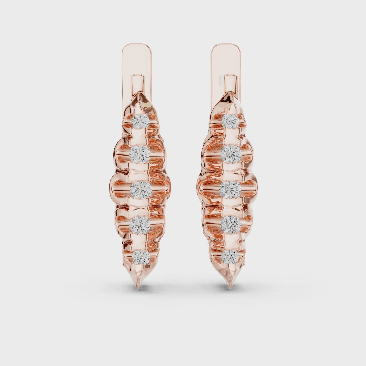Rose gold earrings with diamonds are rotating horizontally on a white surface.