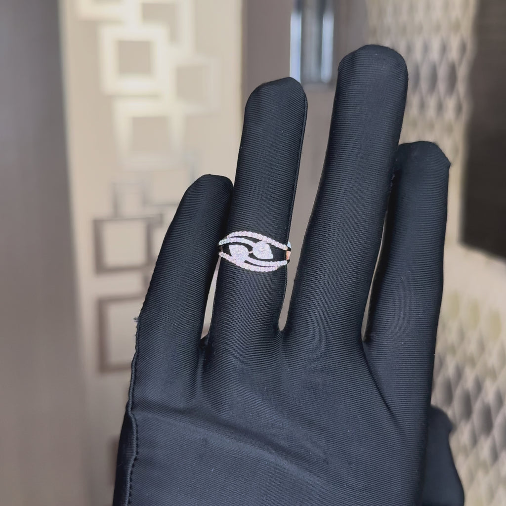 A rose gold ring with pavé-set clear stones, featuring a central pear shape cluster and four curved bands, worn in a hand's finger, which is also worn black gloves. The hand is tilting left and right to show the ring from every angle.