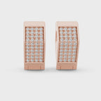 Rose gold earrings with real diamond accents is rotating horizontally on a white surface.