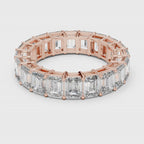 Rose gold ring with emerald-cut natural diamonds on a white surface is rotating all around.
