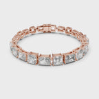 Rose gold bracelet with clear real radiant and emerald shape diamonds rotating horizontally on a white surface.