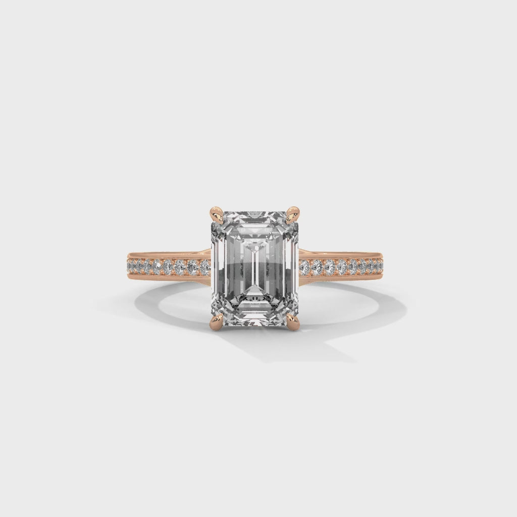 gold ring with emerald-cut diamond and smaller diamonds on a white background is displaying from 360 degree angles