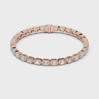 Rose gold bracelet with emerald cut real diamond accents is rotating horizontally on a white surface.