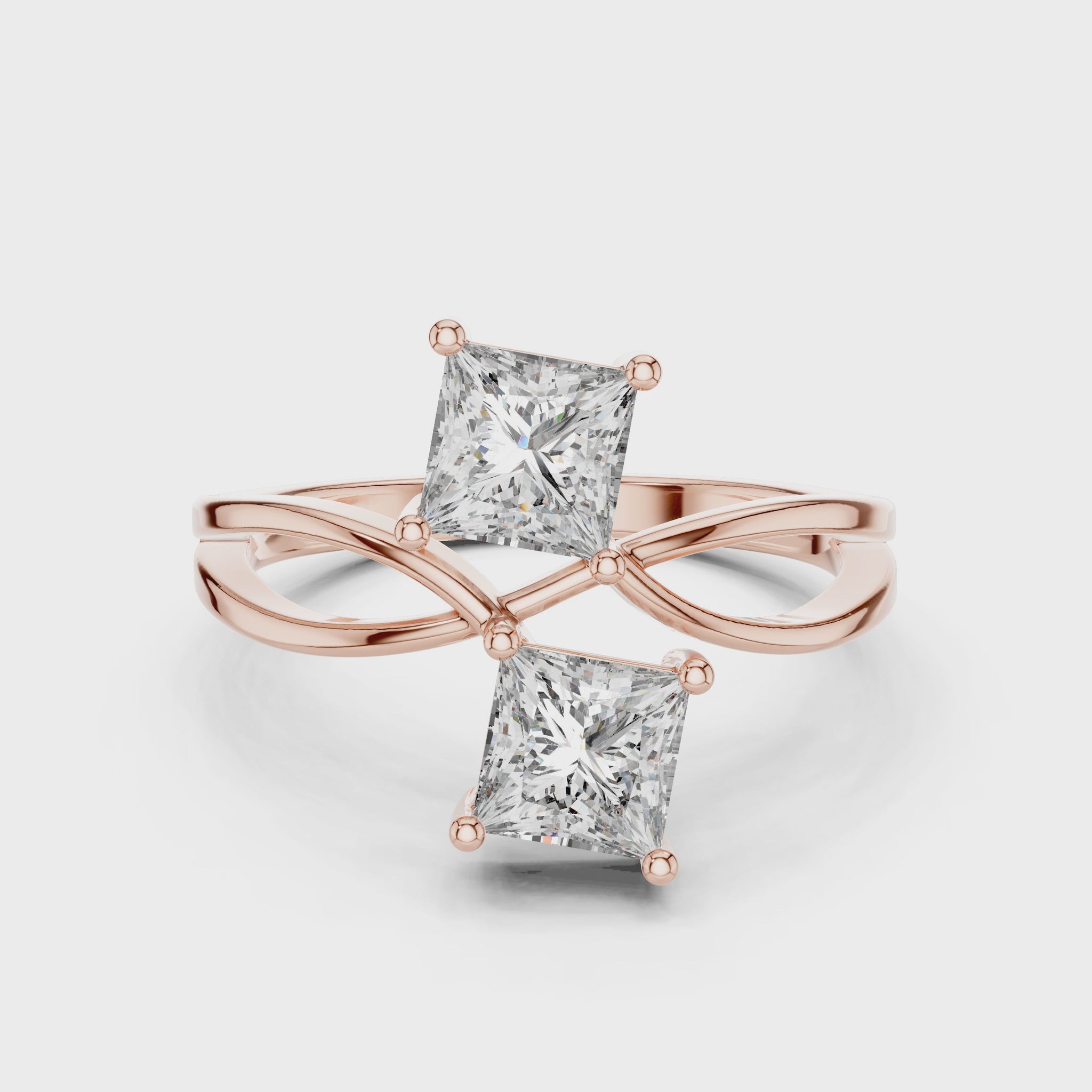 Rose gold ring with two princess-cut lab grown diamonds on a white background, showing from 360 degree angle.