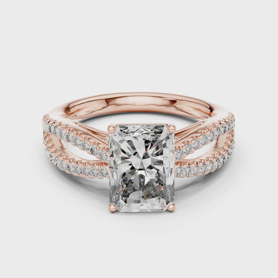 Rose gold ring with a large diamond and smaller diamonds on the band against a white background is rotating on a white surface.