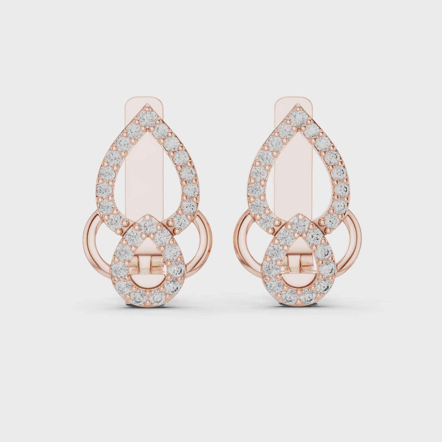 Rose gold earrings with clear diamonds is rotating horizontally on a white surface.
