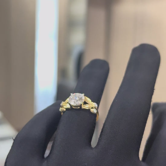 Gold ring with diamond and leaf designs against a natural background