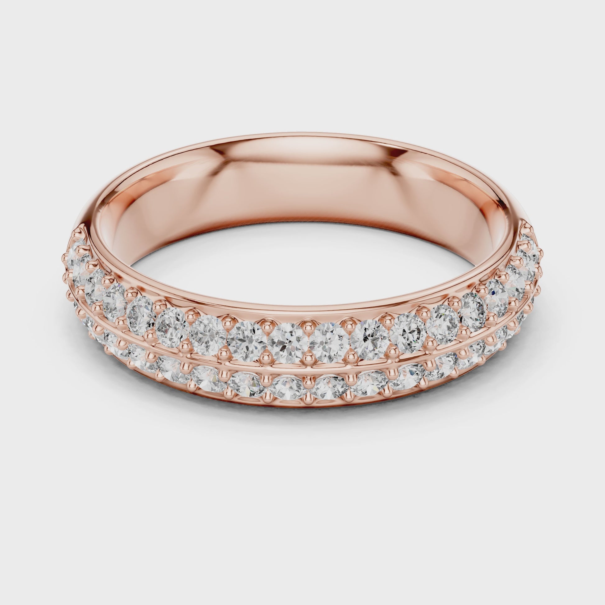 A ring made of rose gold and real diamonds is placed on a white surface and the ring is rotating on the white surface.