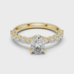 Yellow gold ring studded with a oval shape diamond and some round shape diamonds, rotating on a white surface.