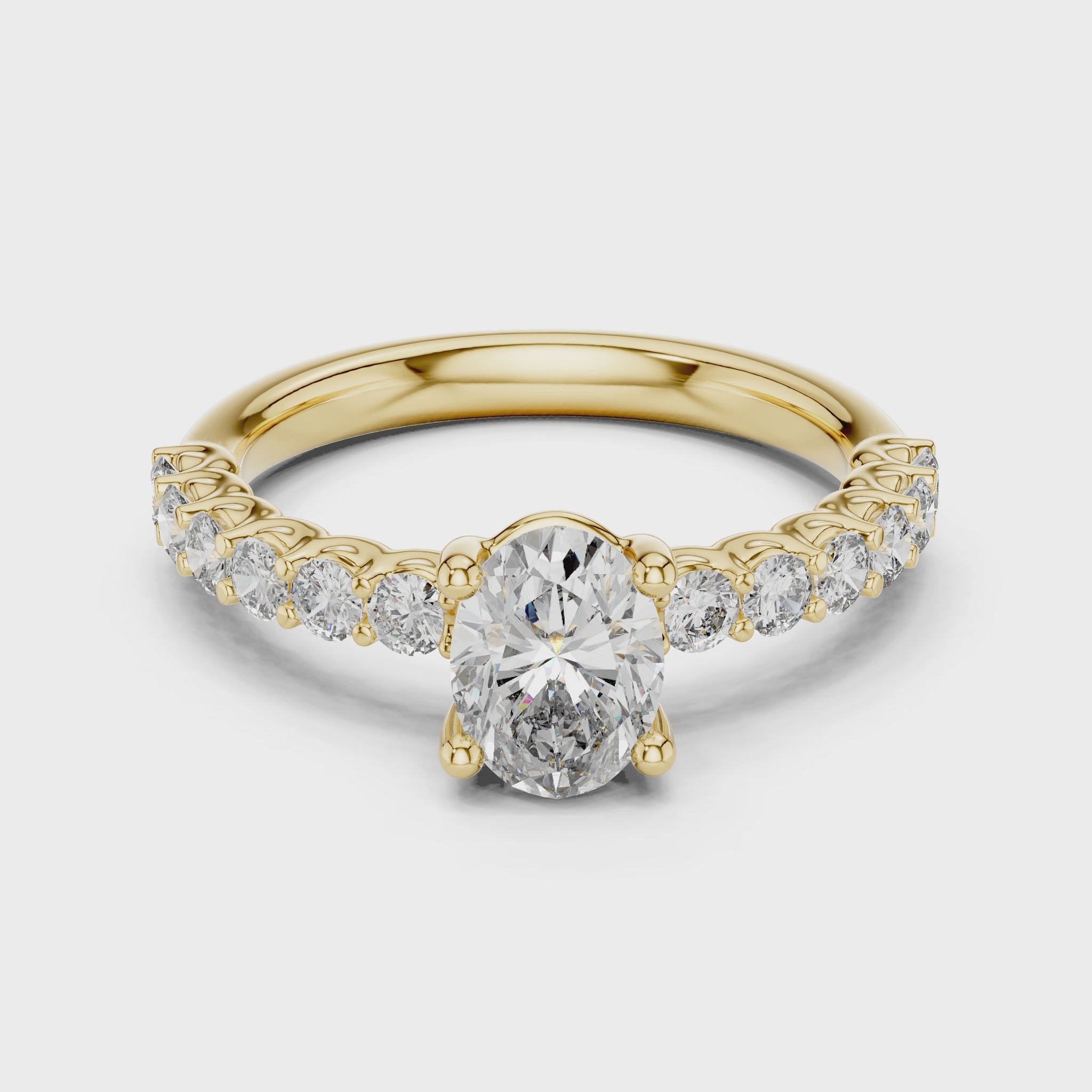 Yellow gold ring studded with a oval shape diamond and some round shape diamonds, rotating on a white surface.