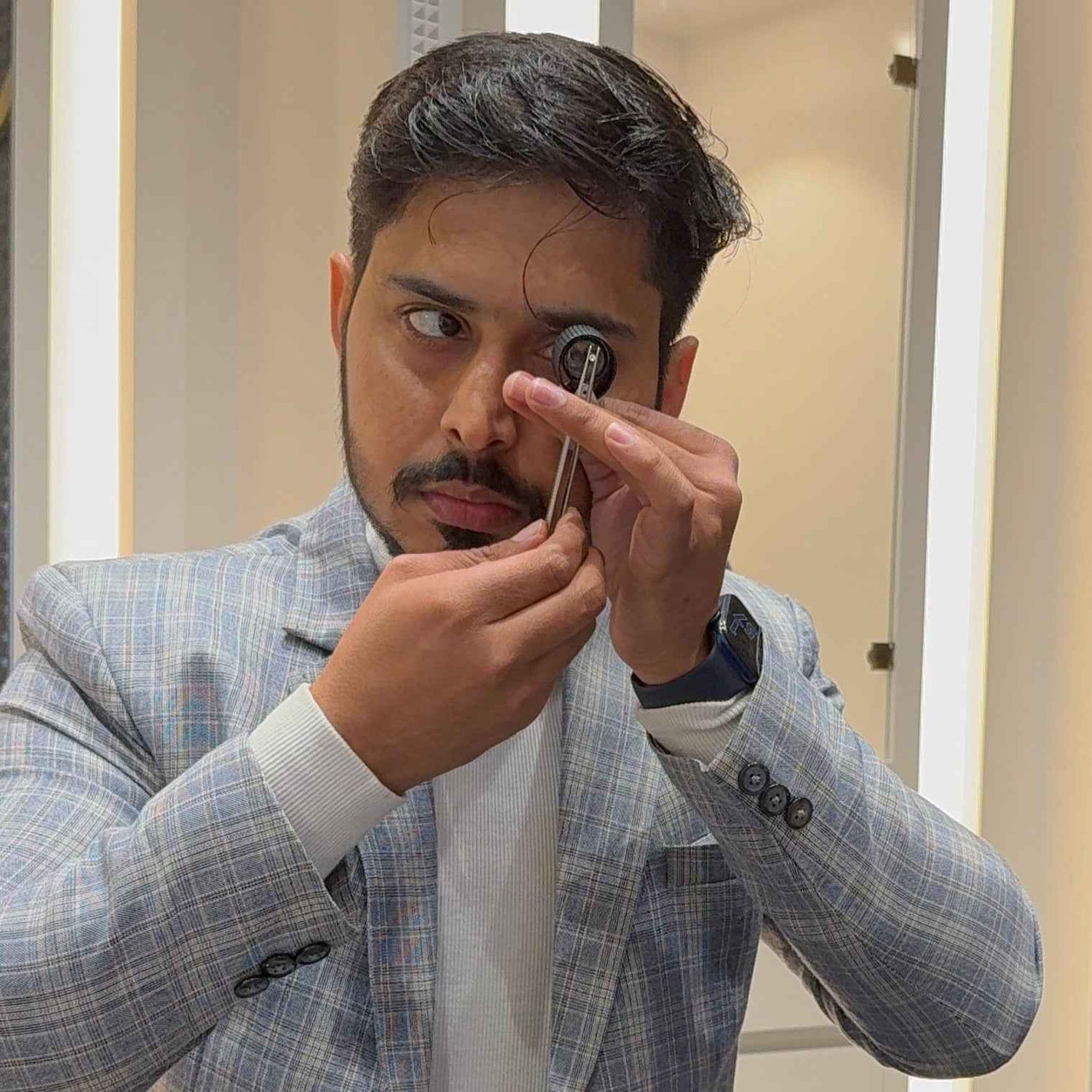 Man in a checkered suit using an otoscope in a clinical setting