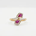 A gold ring with two diamond-paved halos surrounding pink gemstones, displayed on a clean white background.