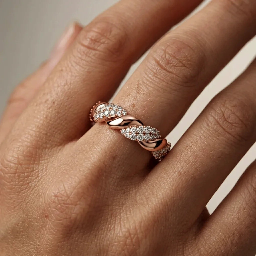 Rose gold ring with diamonds on a hand against a neutral background