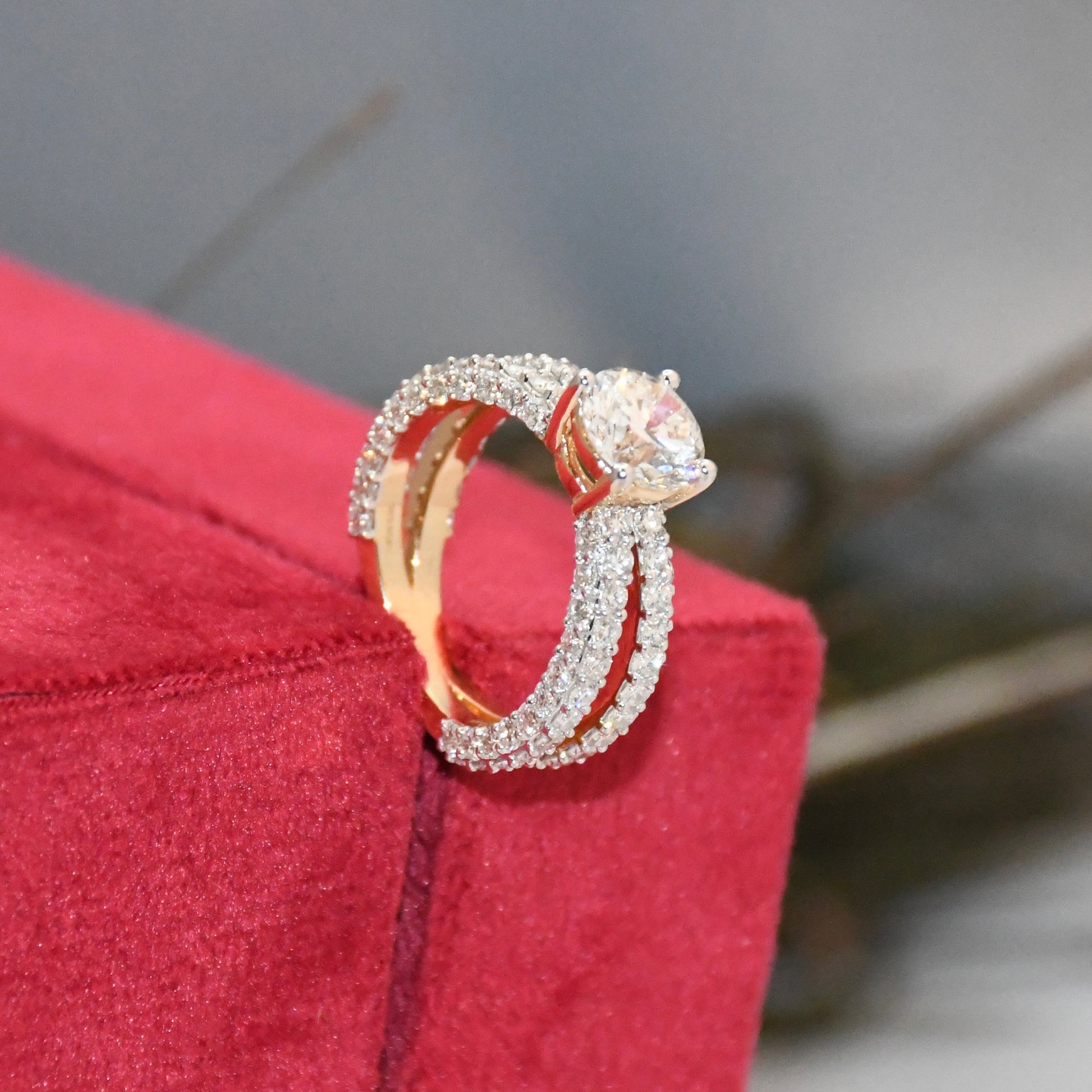Gold and real diamond ring on a red jewelry box with a blurred background