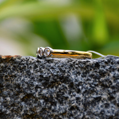 A yellow gold band ring with a series of set diamonds, featuring smaller diamonds, all set in a solid gold band displayed on a black and grey rough surface.
