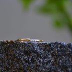 A diamond band ring on a rough textured surface.