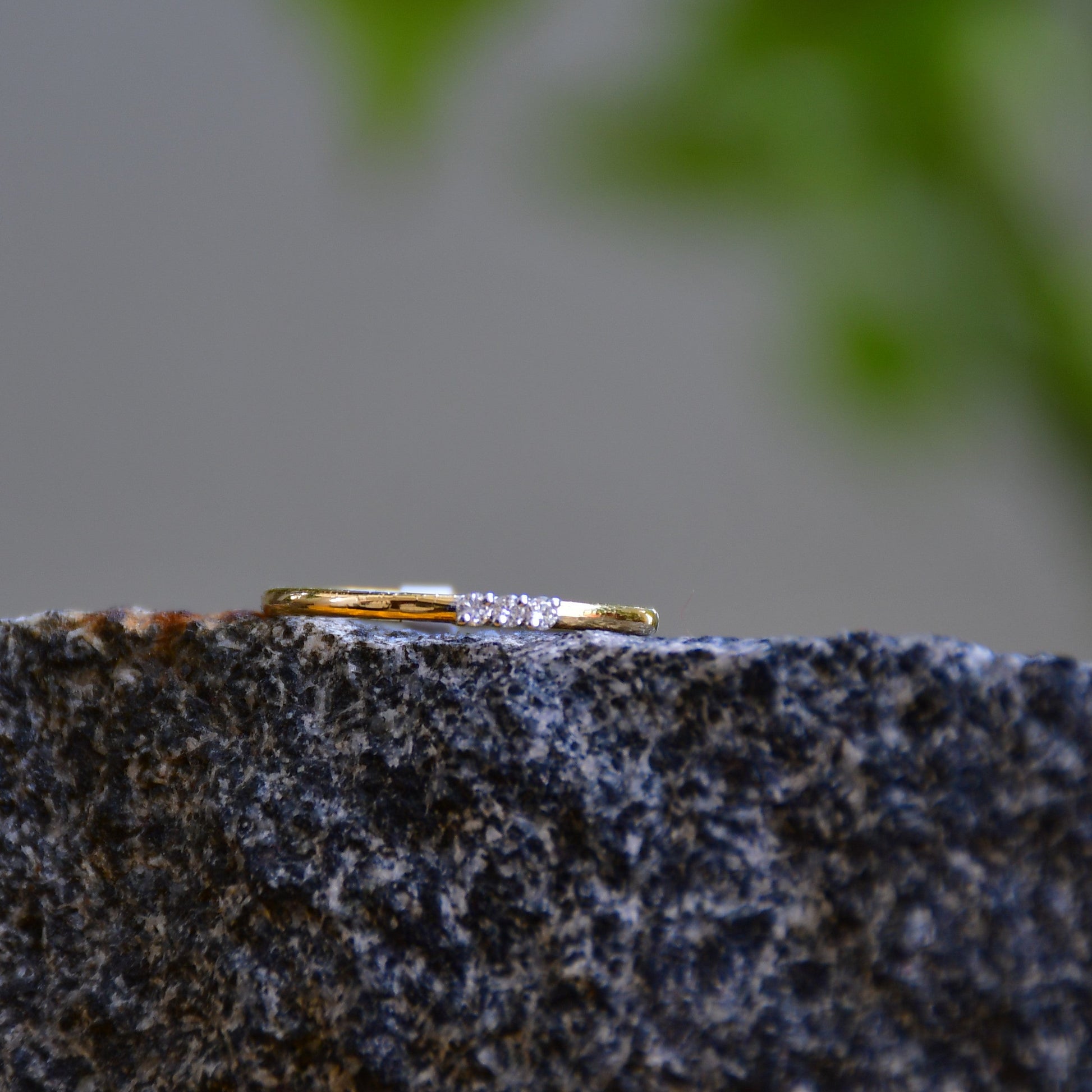A diamond band ring on a rough textured surface.
