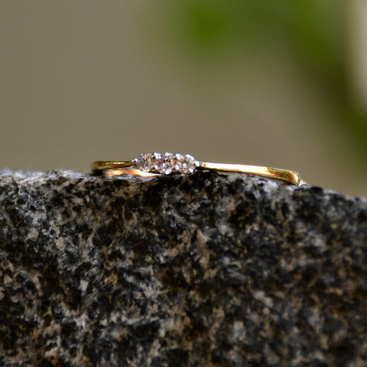 A 14kt gold diamond band ring with three brilliant cut natural diamonds on a textured stone surface.
