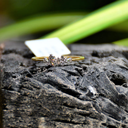 A gold diamond band ring set on a dark stone surface with a blurred green background.