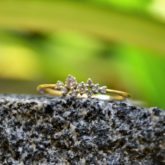 A gold diamond band ring set on a stone surface with a blurred green background.