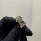 Elegant gold diamond ring featuring a round-cut central diamond surrounded by a halo of smaller diamonds, set on a split shank band adorned with rows of sparkling pavé diamonds, displayed on a black gloved hand against a neutral background.