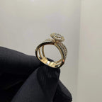 Elegant gold diamond ring featuring a round-cut central diamond surrounded by a halo of smaller diamonds, set on a split shank band adorned with rows of sparkling pavé diamonds, displayed on a black gloved hand against a neutral background.