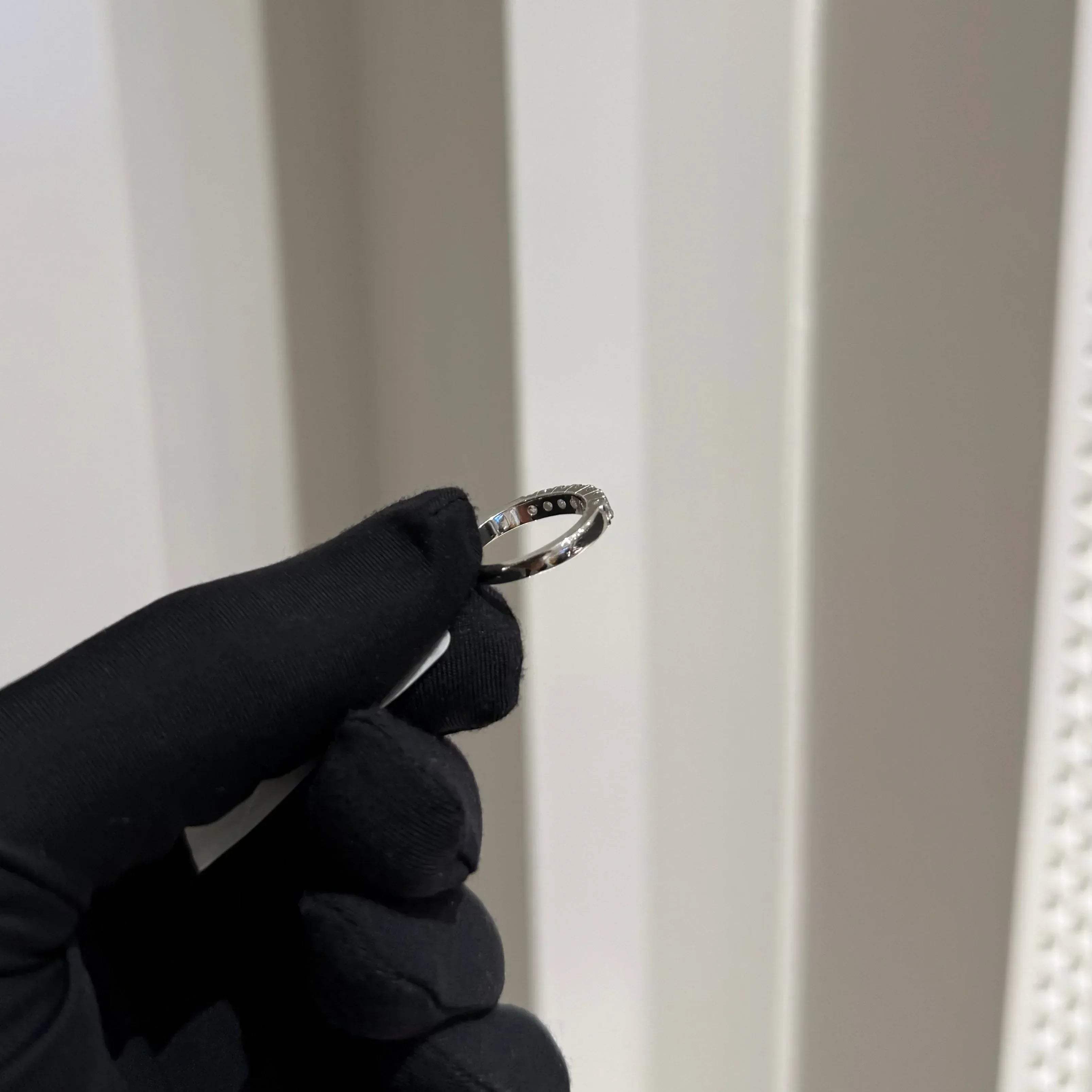 A band diamond ring with multiple stones set in a gold band, displayed on a black glove against a neutral background.
