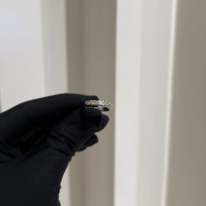 A band diamond ring with multiple stones set in a gold band, displayed on a black glove against a neutral background.