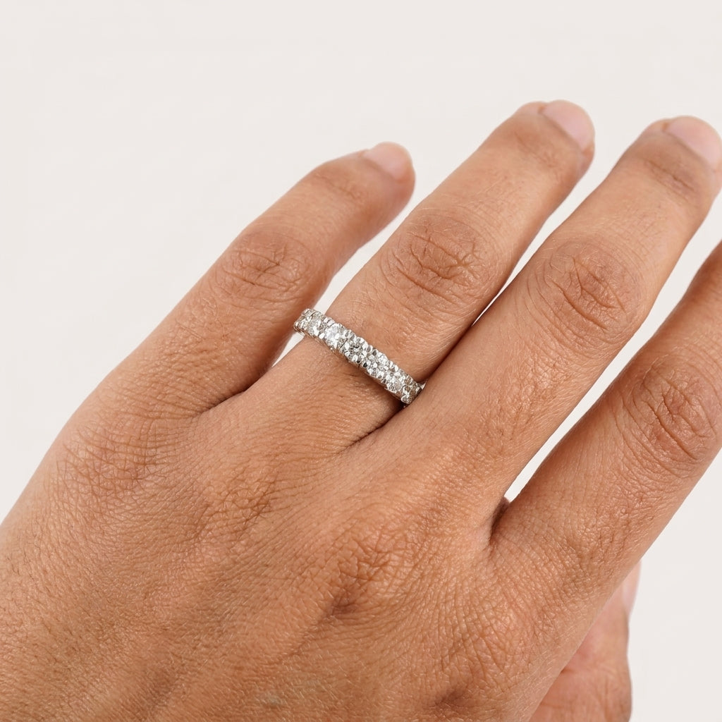 A close-up of band diamond ring with multiple diamonds set in a gold band, displayed in a hand's finger.