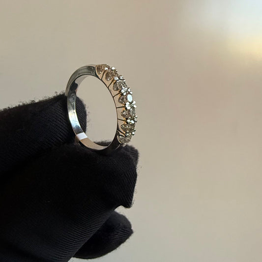 A band diamond ring with multiple stones set in a gold band, displayed on a black glove against a neutral background.