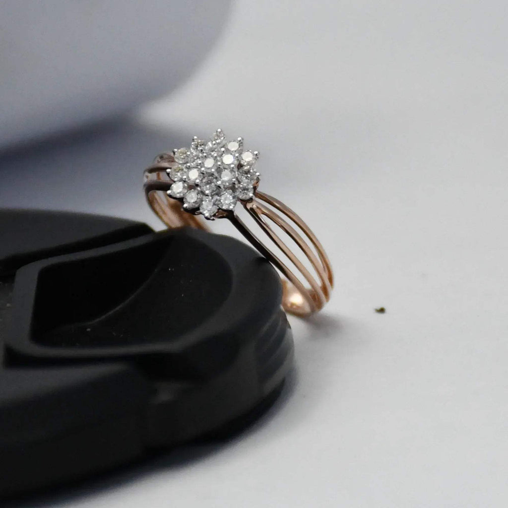 Rose gold ring with diamond cluster on a black surface