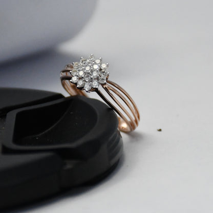 Rose gold ring with diamond cluster on a black surface