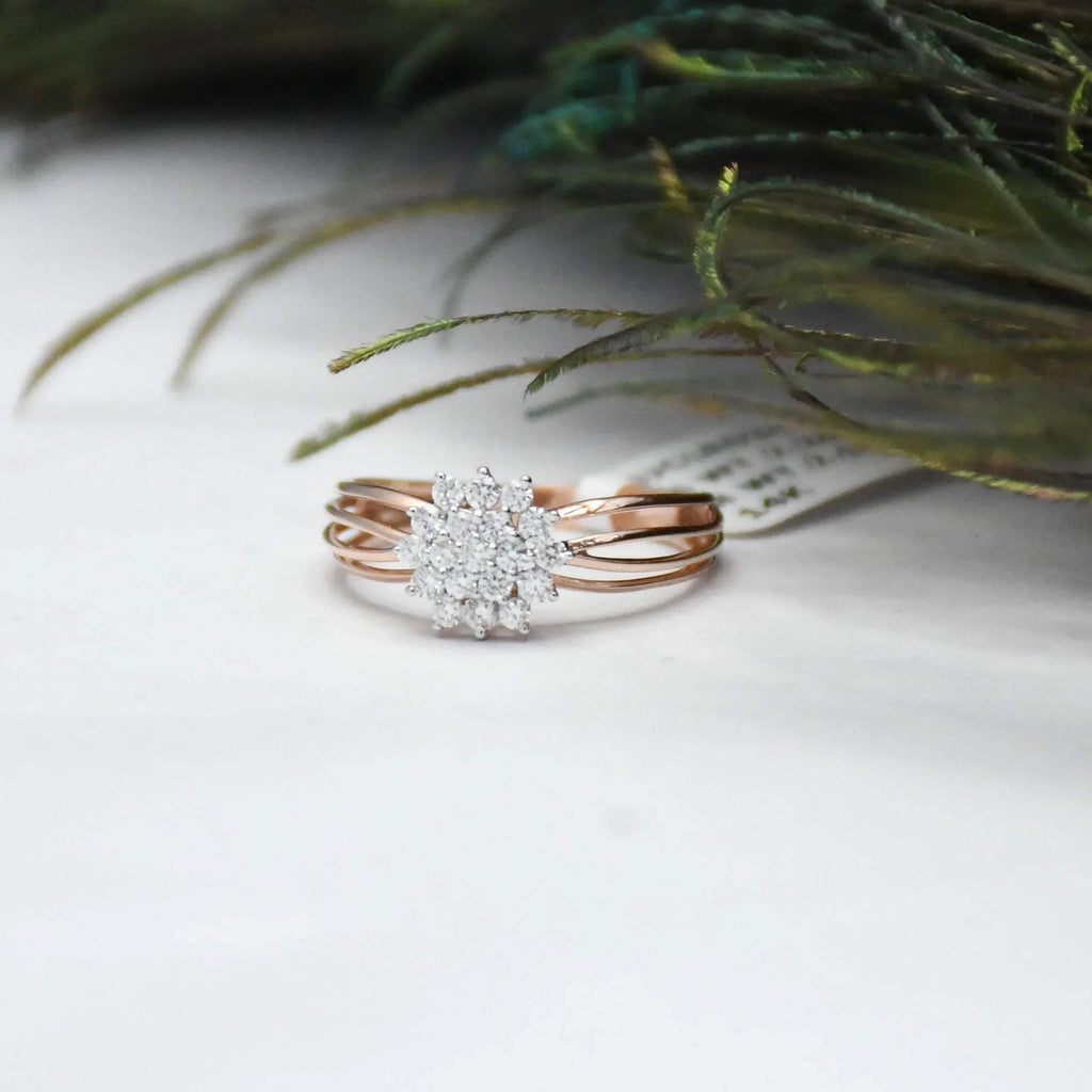 Rose gold ring with diamond accents on a white surface with greenery.