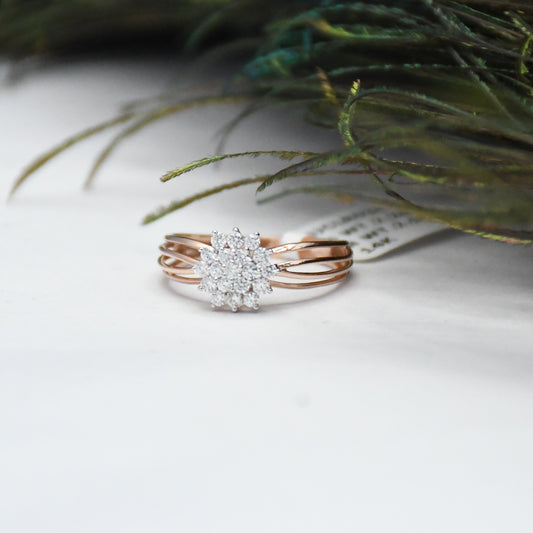 Rose gold ring with diamond accents on a white surface with greenery.