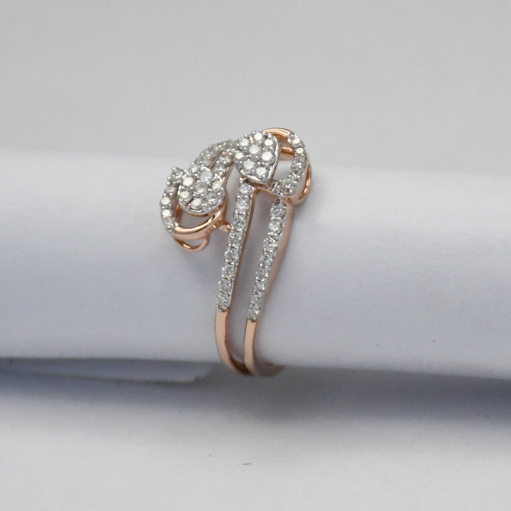 Rose gold ring with diamonds on a light gray background