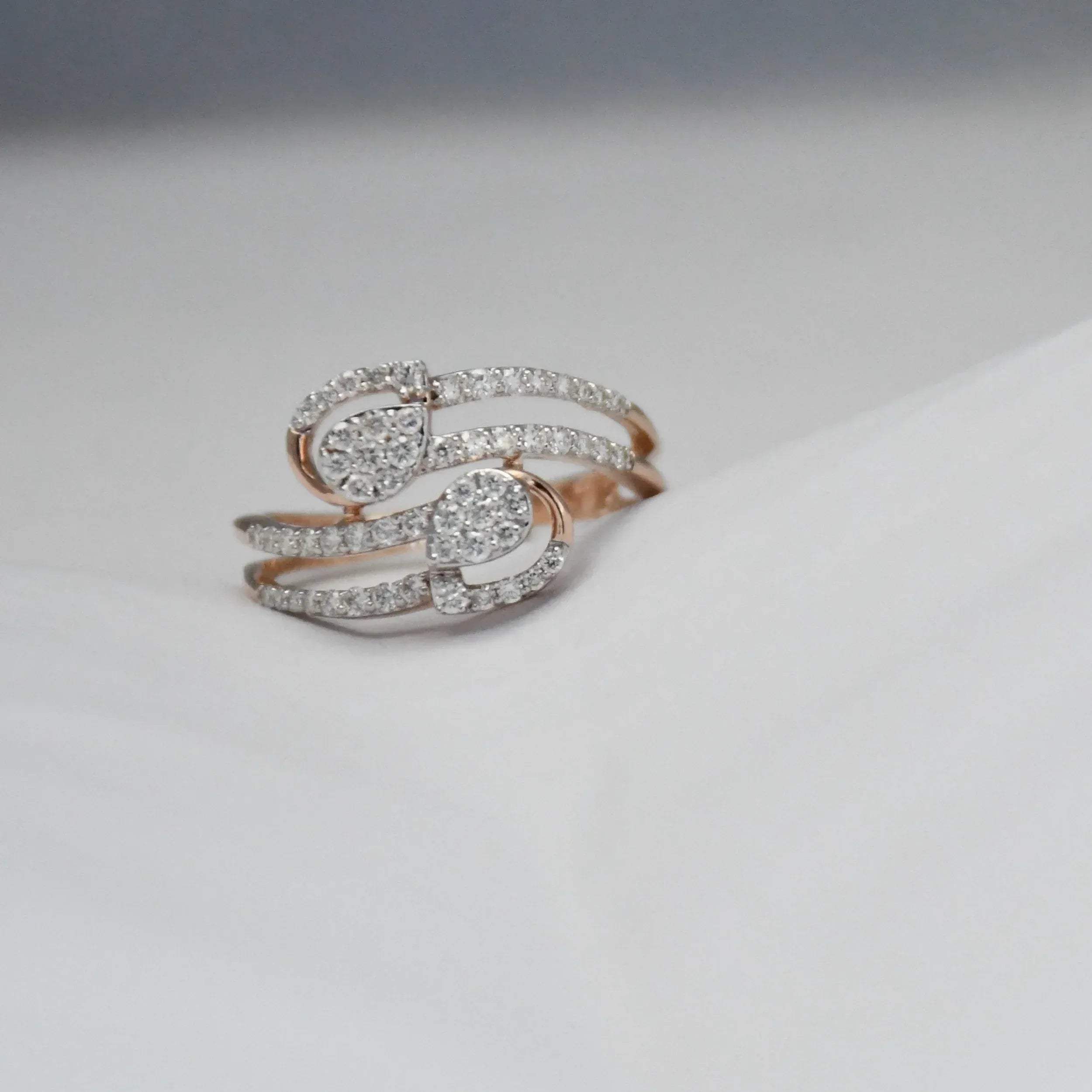 Rose gold ring with diamonds on a light gray background