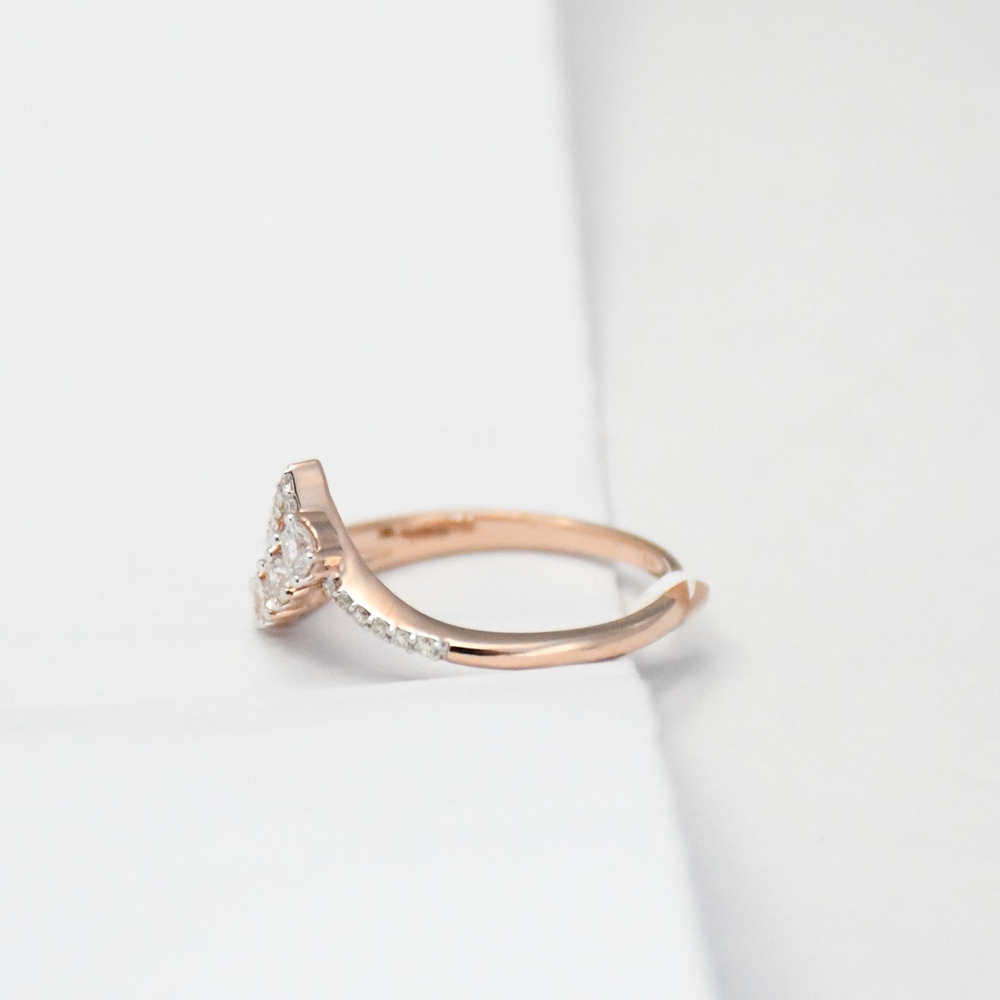 Rose gold ring with diamonds on a light gray background