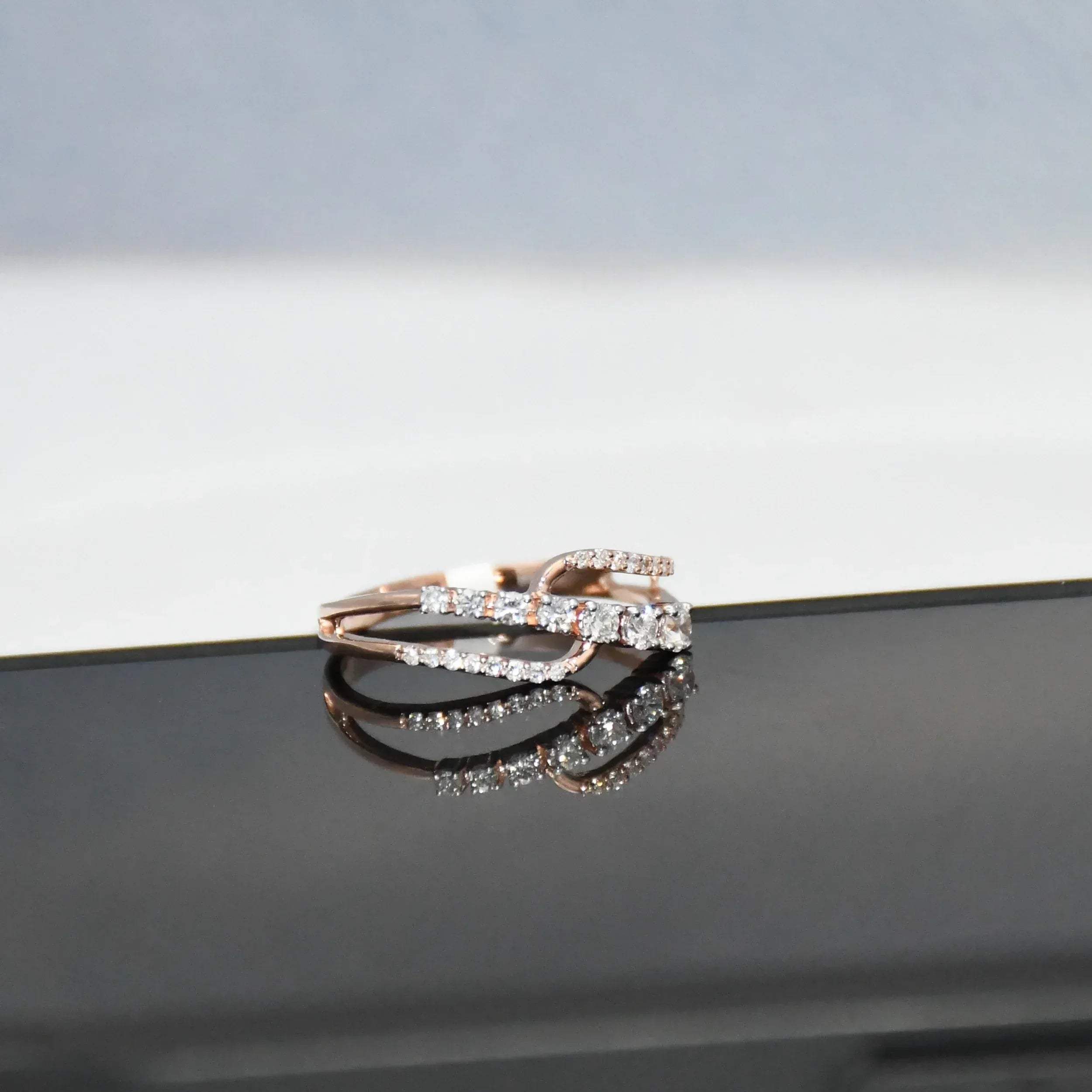 gold ring with diamonds on a reflective surface