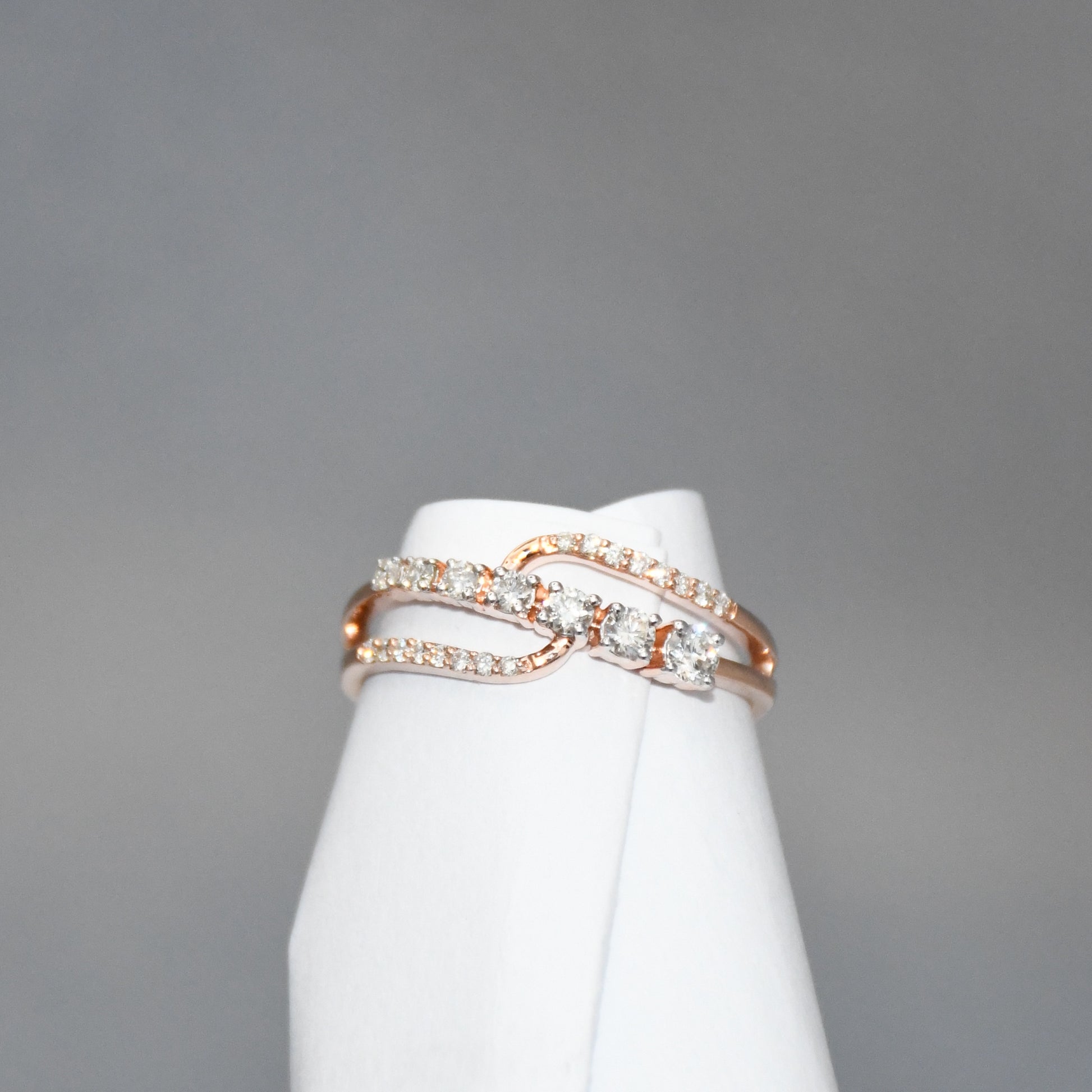 gold ring with diamonds on a white stand against a gray background