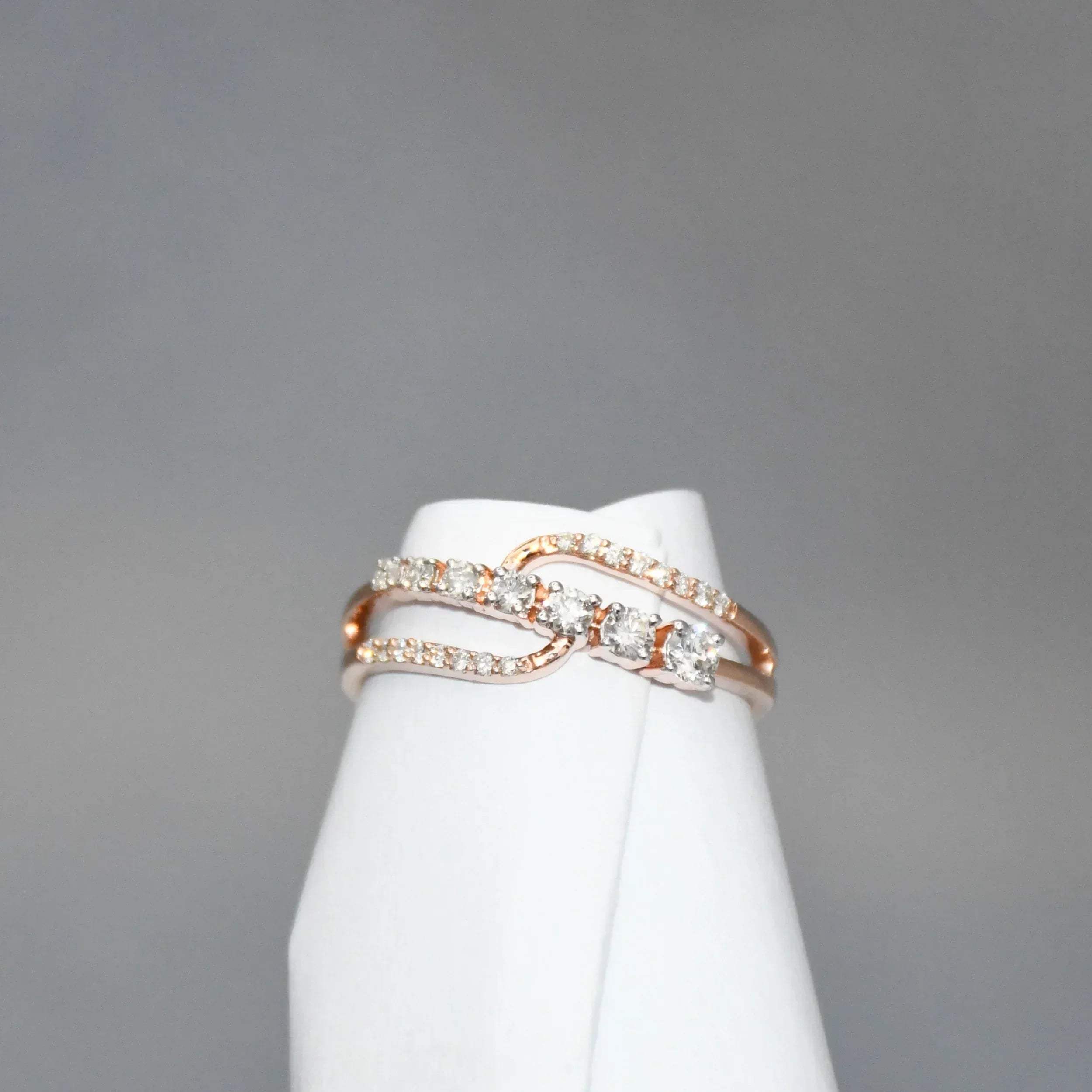 gold ring with diamonds on a white stand against a gray background